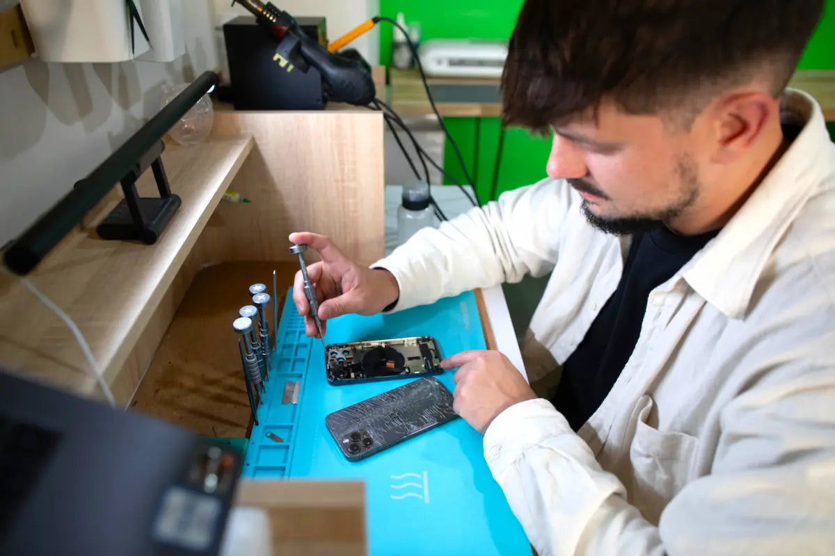 Technicien iTelier en pleine réparation de smartphone à Lyon 6 dans l’atelier, remplacement d’écran iPhone avec outils professionnels sur poste de travail
