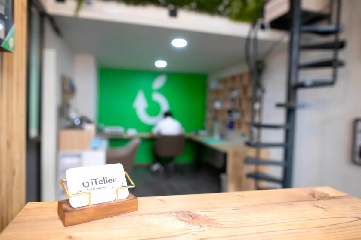 Photo de l’atelier iTelier à Lyon avec carte de visite en avant-plan, service de réparation de smartphones, tablettes et ordinateurs pour professionnels.