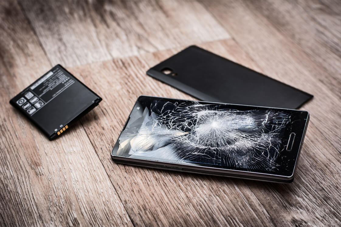 Smartphone avec écran cassé et batterie retirée sur plan de travail, pris en charge chez iTelier Lyon pour diagnostic et réparation rapide avec pièces garanties