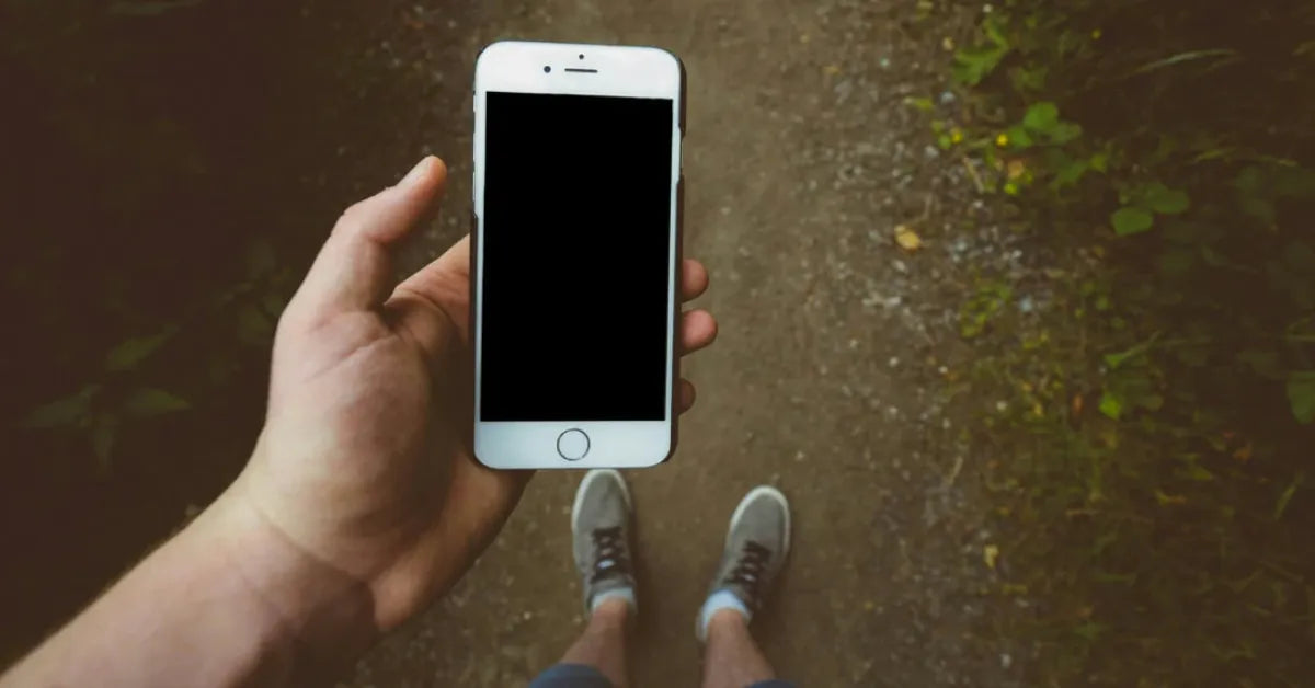 Main tenant un smartphone en extérieur, illustrant la garantie 1 an offerte par iTelier à Lyon pour toutes réparations de téléphones avec pièces d’origine.