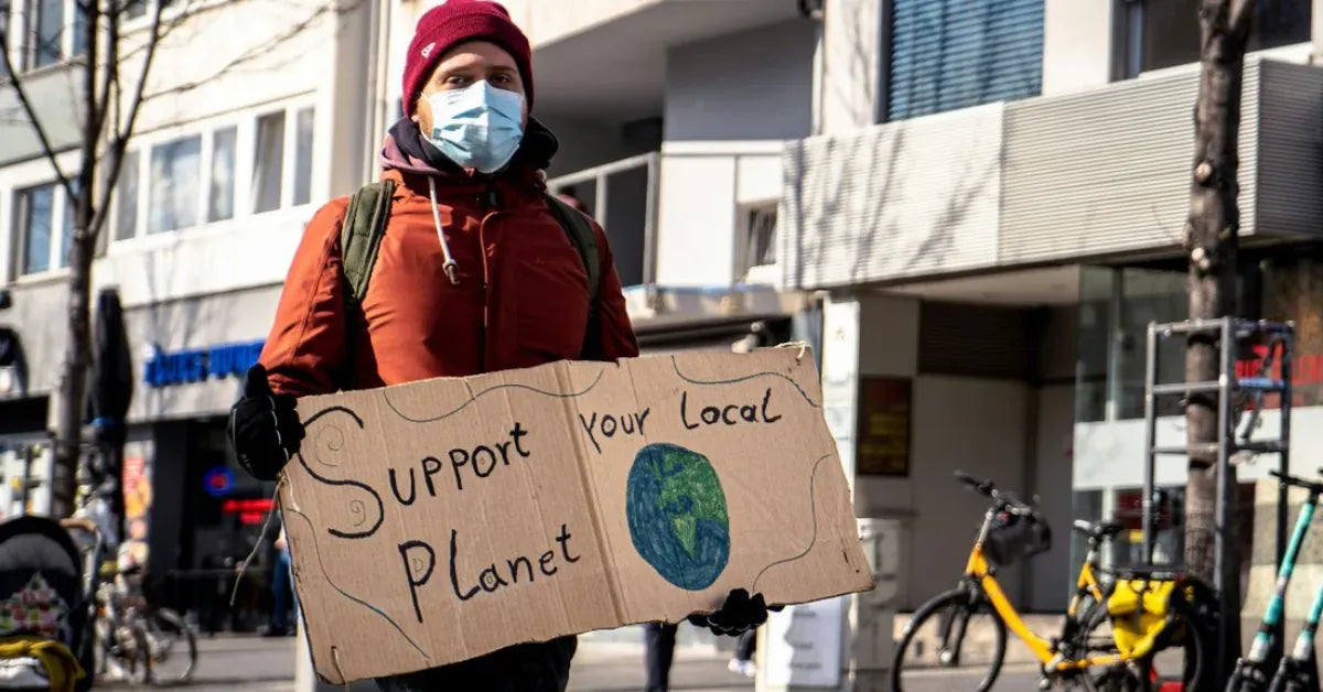 Personne tenant une pancarte de sensibilisation à l’écologie, illustrant l’engagement d’iTelier à Lyon pour les smartphones reconditionnés et la réduction des déchets électroniques.